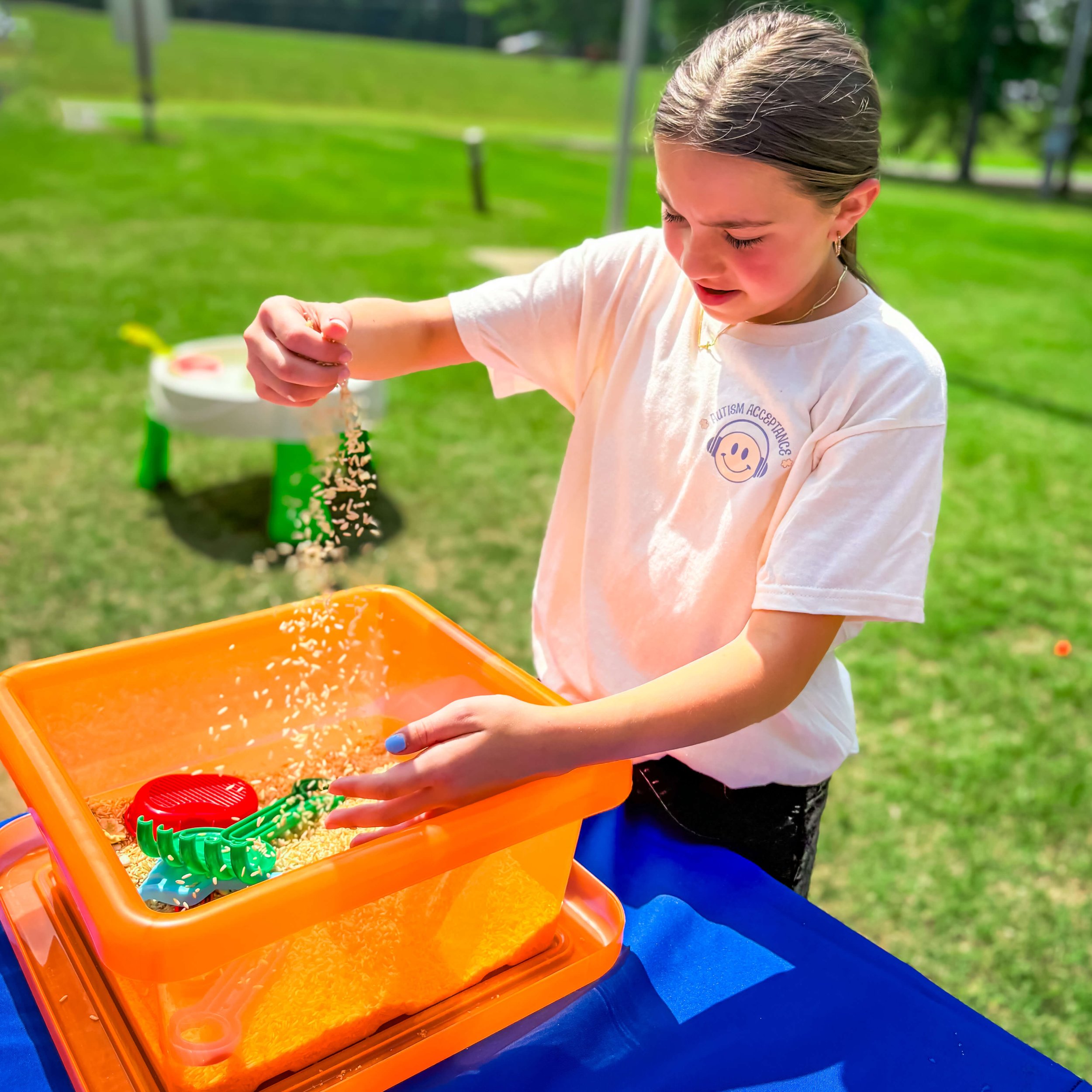 A child exploring a sensory bin outdoors during therapy