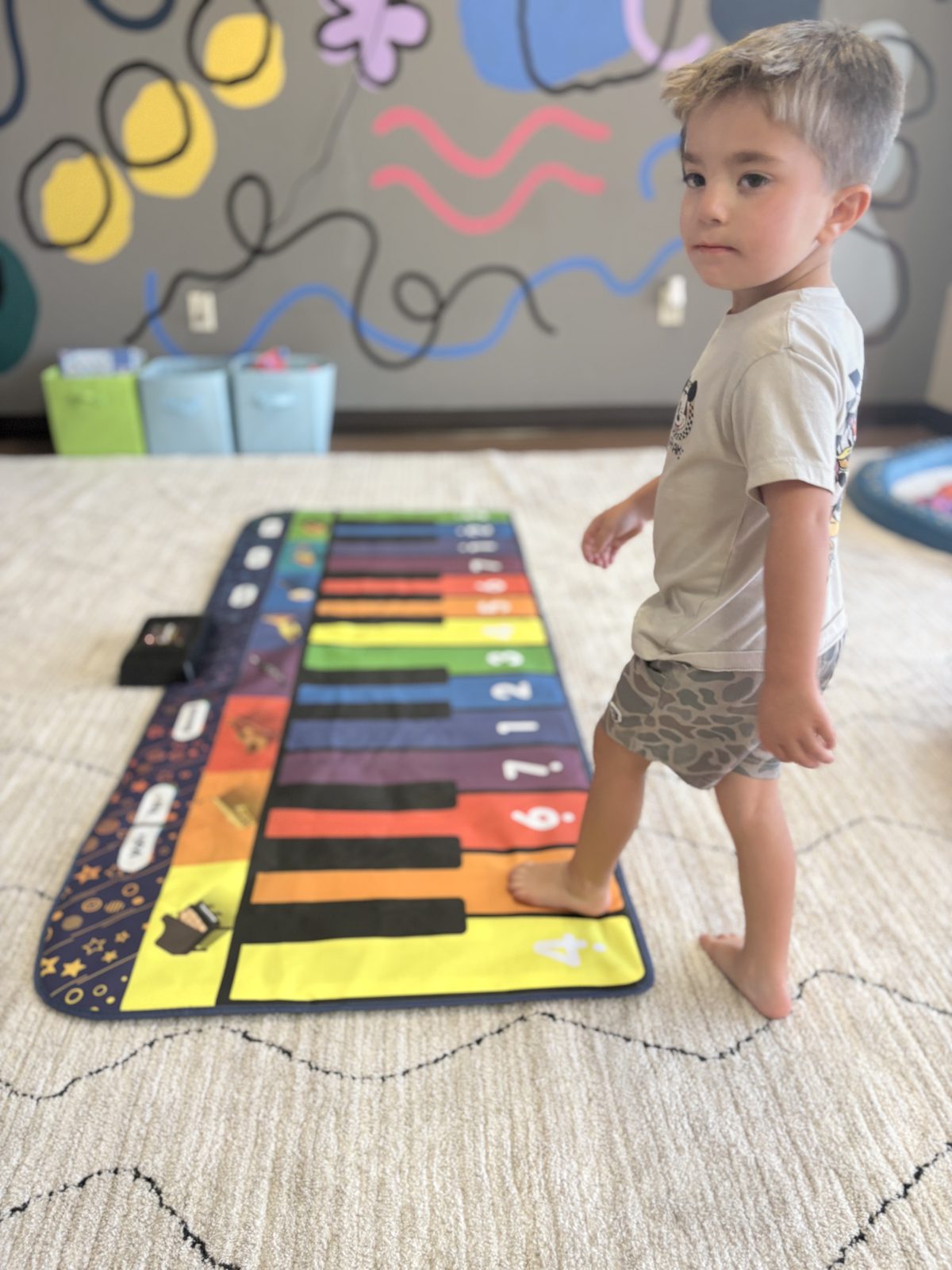 A young boy playing on a giant rainbow piano mat at our clinic